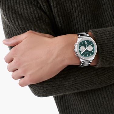 Piaget PoloChronograph Hand wearing a watch with a green face on a dark background